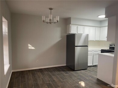 Kitchen featuring black electric range oven, an inviting chandelier, hanging light fixtures, stainless steel refrigerator, and white cabinets