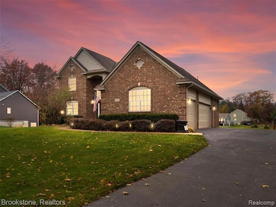 View of front of property with brick siding, a lawn, driveway, and a garage