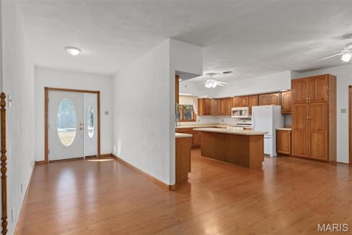 Kitchen with brown cabinets, a center island, light countertops, light wood-type flooring, and healthy amount of natural light