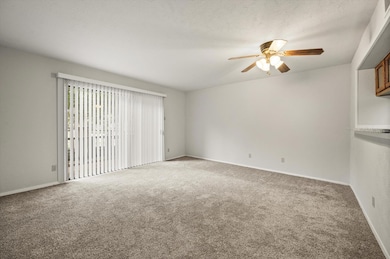 Spare room featuring carpet flooring, a textured ceiling, and ceiling fan