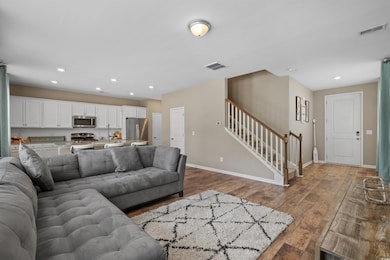 Living room featuring stairs, wood-type flooring, and recessed lighting