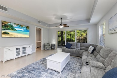 Tiled living area featuring plenty of natural light, a ceiling fan, and a tray ceiling