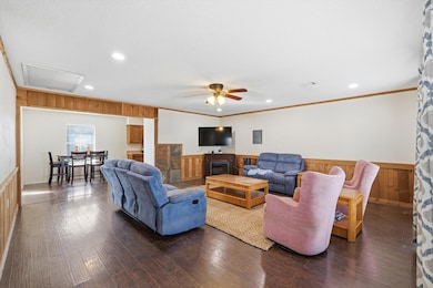 Living area featuring a wainscoted wall, wooden walls, wood finished floors, crown molding, and recessed lighting