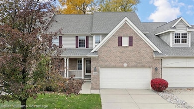 View of front of property with roof with shingles, covered porch, concrete driveway, a front yard, and an attached garage