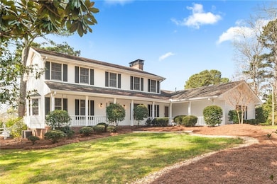 View of front of house featuring covered porch, a chimney, and a front lawn