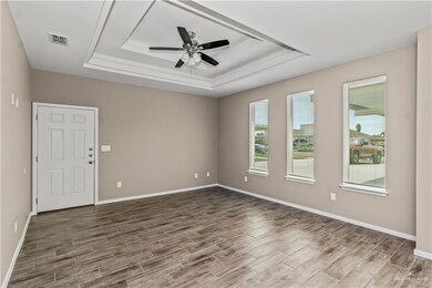 Unfurnished room with hardwood / wood-style flooring, ceiling fan, and a tray ceiling