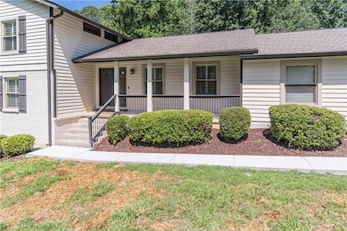 Split level home with a porch, roof with shingles, and a front yard