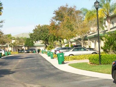 Exterior Front. Wide winding palm tree lined stree