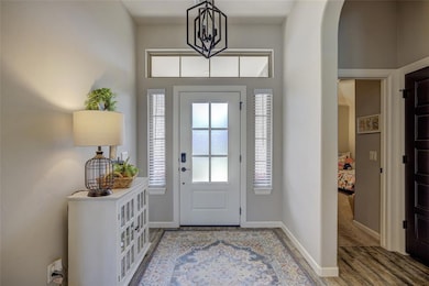 Foyer entrance with arched walkways, wood finished floors, and baseboards