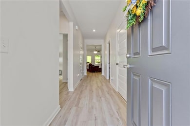 Hallway with light wood-type flooring and recessed lighting