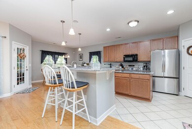 Kitchen with appliances with stainless steel finishes, a kitchen breakfast bar, light hardwood / wood-style floors, decorative light fixtures, and a center island with sink