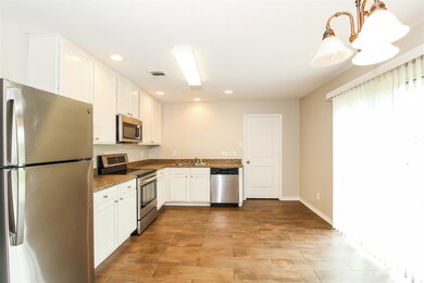 Kitchen with sink, white cabinetry, dark stone counters, stainless steel appliances, and pendant lighting