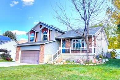 View of front of property featuring an attached garage, driveway, brick siding, and covered porch