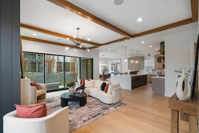 Living area with beam ceiling, light wood-style flooring, a chandelier, and recessed lighting