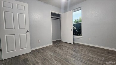Unfurnished bedroom with dark wood finished floors, baseboards, a closet, and a textured wall