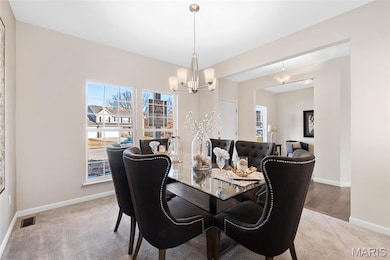 Dining area with light colored carpet and a chandelier
