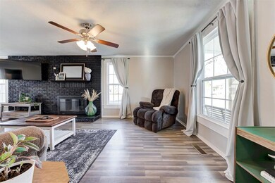 Living room with ceiling fan, a fireplace, brick w
