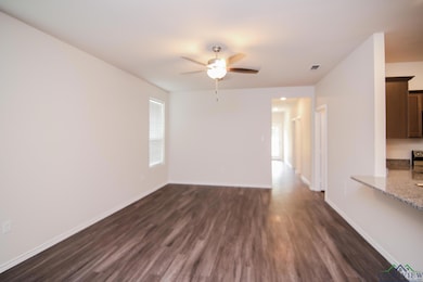 Unfurnished room with ceiling fan, dark wood-style flooring, plenty of natural light, and baseboards