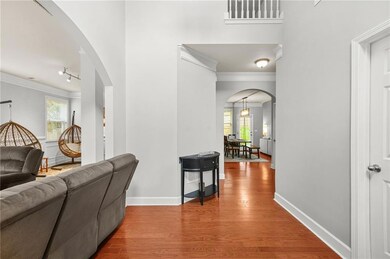 Hall featuring ornamental molding, arched walkways, wood finished floors, and plenty of natural light