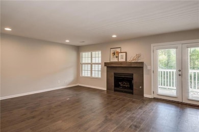 Unfurnished living room with french doors, dark wood-style floors, recessed lighting, and a fireplace