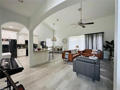 Living area featuring ceiling fan, light wood finished floors, high vaulted ceiling, and arched walkways