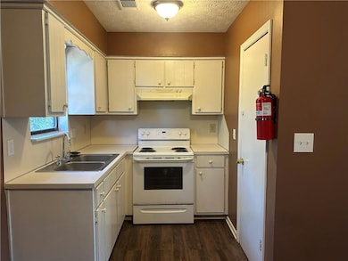 Kitchen with electric stove, light countertops, dark wood-style floors, a textured ceiling, and under cabinet range hood