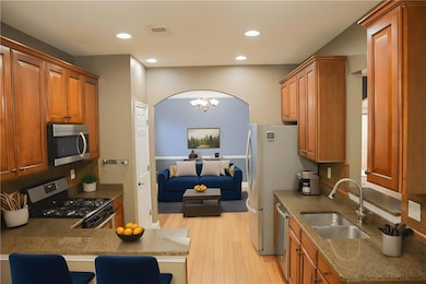 Kitchen featuring light wood-style floors, light stone counters, appliances with stainless steel finishes, a chandelier, and recessed lighting
