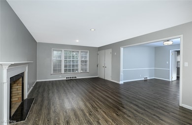 Unfurnished living room featuring dark wood-type flooring, recessed lighting, and a fireplace with raised hearth