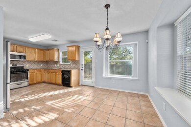 Kitchen with tasteful backsplash, light tile patterned floors, appliances with stainless steel finishes, a chandelier, and hanging light fixtures