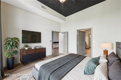 Bedroom featuring a towering ceiling, light wood-type flooring, baseboards, and ceiling fan
