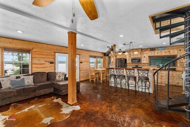 Living room with ceiling fan, plenty of natural light, a textured ceiling, and wooden walls