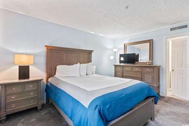Bedroom featuring dark carpet, crown molding, and a textured ceiling