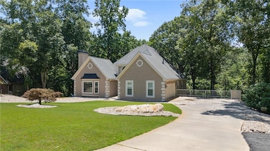 View of front of property featuring driveway, stucco siding, a chimney, and a standing seam roof