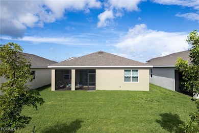 Back of property with a sunroom, a shingled roof, stucco siding, and a yard