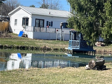 Rear view of property with a lawn, metal roof, and a deck with water view