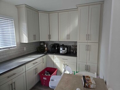 Kitchen with dark countertops, white cabinetry, an