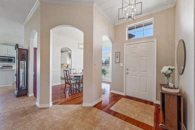 Foyer with ornamental molding, a high ceiling, arched walkways, and light wood-type flooring