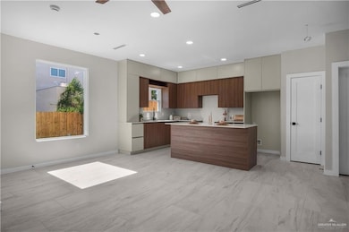 Kitchen featuring modern cabinets, light countertops, a center island, recessed lighting, and open floor plan