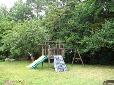 Wooded backyard with playset.