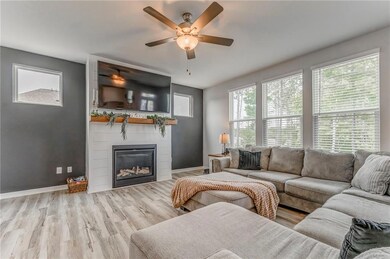 Living room featuring ceiling fan, a fireplace, wood finished floors, and baseboards