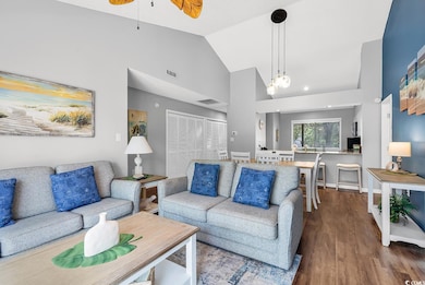 Living room featuring high vaulted ceiling, wood finished floors, and a ceiling fan