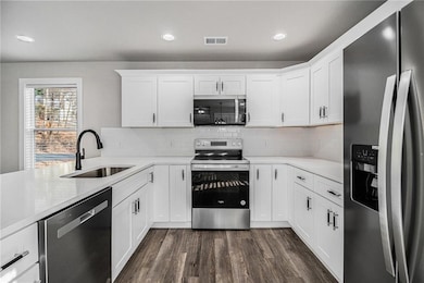Kitchen with white cabinets, appliances with stain