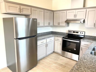 Kitchen featuring appliances with stainless steel finishes, dark stone countertops, and under cabinet range hood