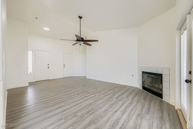 Unfurnished living room with a fireplace, lofted ceiling, light wood-style flooring, and ceiling fan