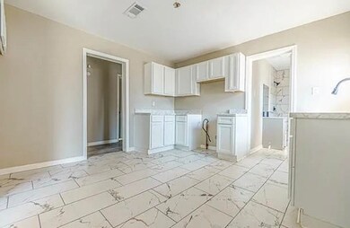 Kitchen with white cabinets, light marble finish floors, and light countertops