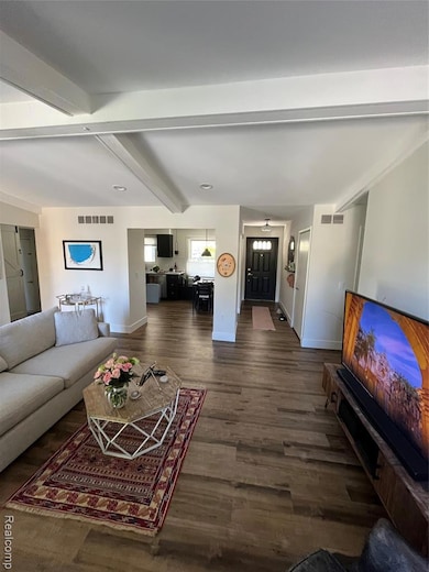 Living area featuring beam ceiling and dark wood finished floors