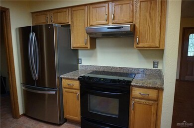 Kitchen with tile patterned flooring, stainless steel refrigerator, and black range with electric stovetop
