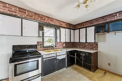 Kitchen featuring white cabinets, stainless steel electric range oven, light flooring, light countertops, and a textured ceiling