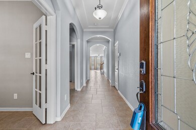 Inviting entryway into the home with crown molding, high ceilings, & arched doorways.