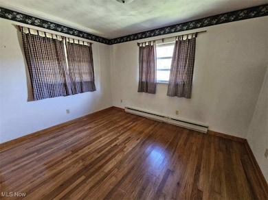 Spare room with a baseboard heating unit and dark wood-style flooring